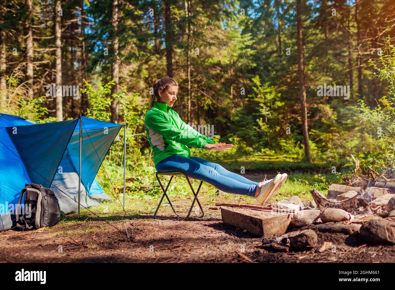 Donna rilassante da falò in foresta seduta accanto a tenda riscaldamento  mani e piedi. Campeggio estivo. Viaggiando da solo Foto stock - Alamy