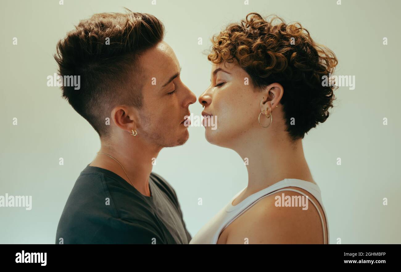 Romantica coppia queer giovane andare in per un bacio. Affettuoso giovane coppia queer in piedi l'uno vicino all'altro con gli occhi chiusi. Giovane cou LGBTQ+ Foto Stock