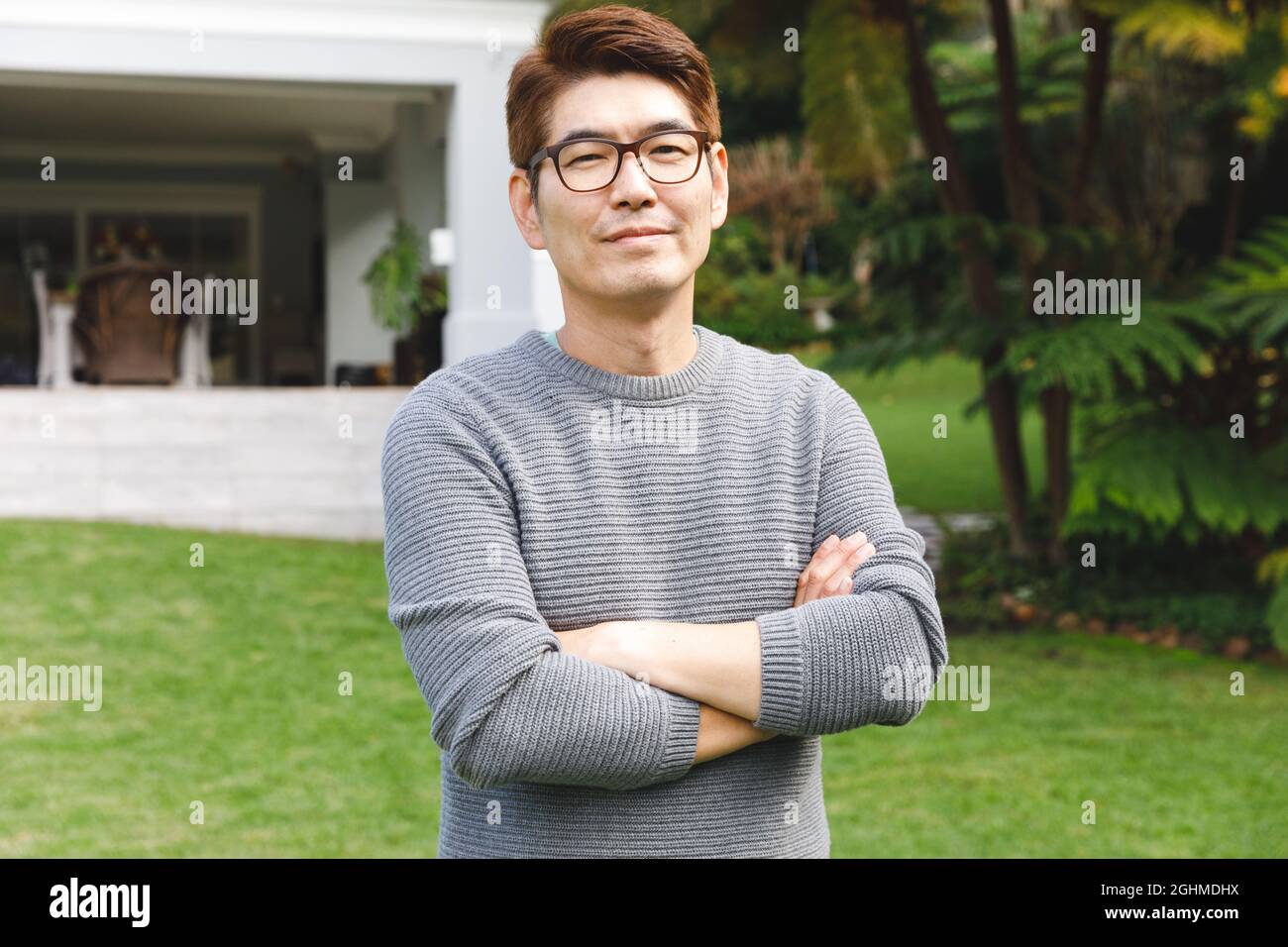 Ritratto di uomo asiatico felice indossare occhiali sorridenti in giardino fuori casa famiglia Foto Stock