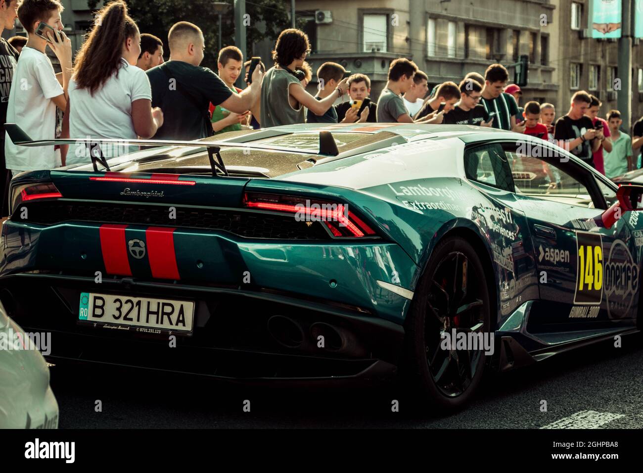 Una Lamborghini blu con un lavoro di verniciatura personalizzato che passa da una folla allegra di fan Foto Stock