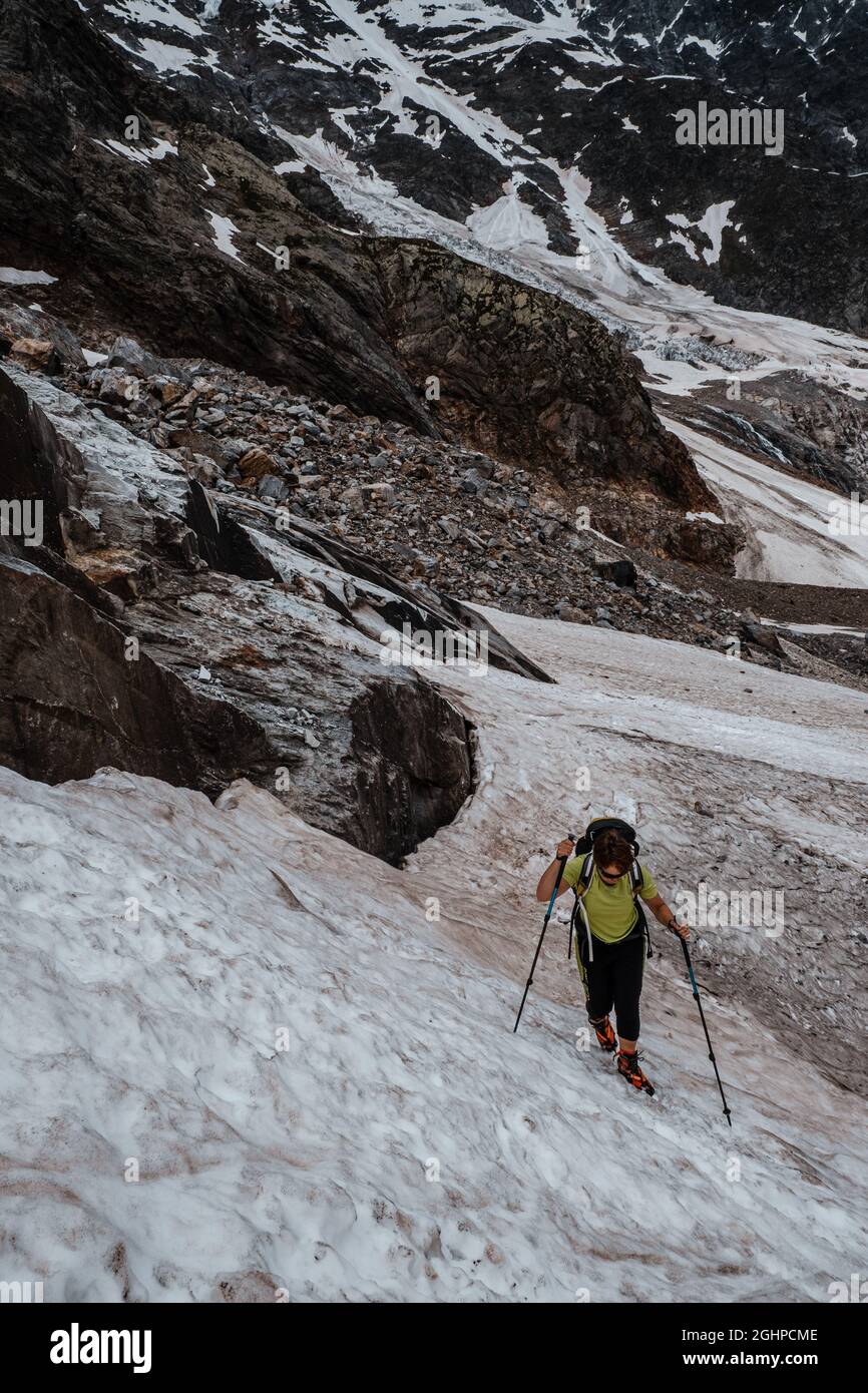 Donna con racchette da neve che attraversano un ghiacciaio, la catena montuosa del Monte Rosa, le Alpi italiane Foto Stock