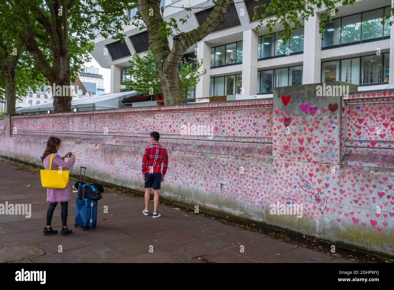 Londra, Regno Unito - 30 luglio 2021: Una ragazza scatta una foto del suo coniuge in piedi presso il National Covid Memorial Wall a Southbank, coperto di thous Foto Stock