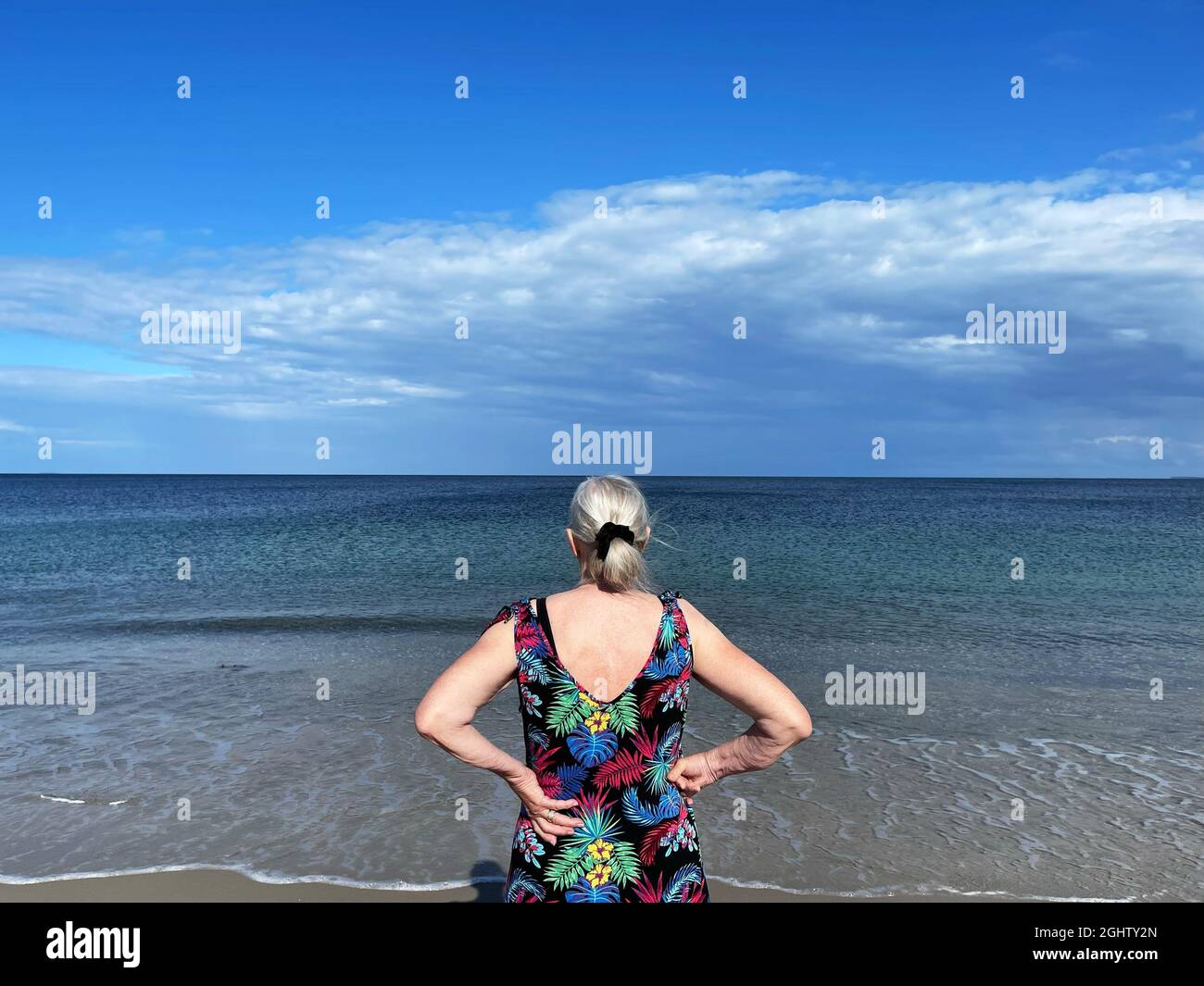 Vista posteriore di una donna anziana in piedi sulla spiaggia che guarda al mare, Samsoe, Jutland, Danimarca Foto Stock