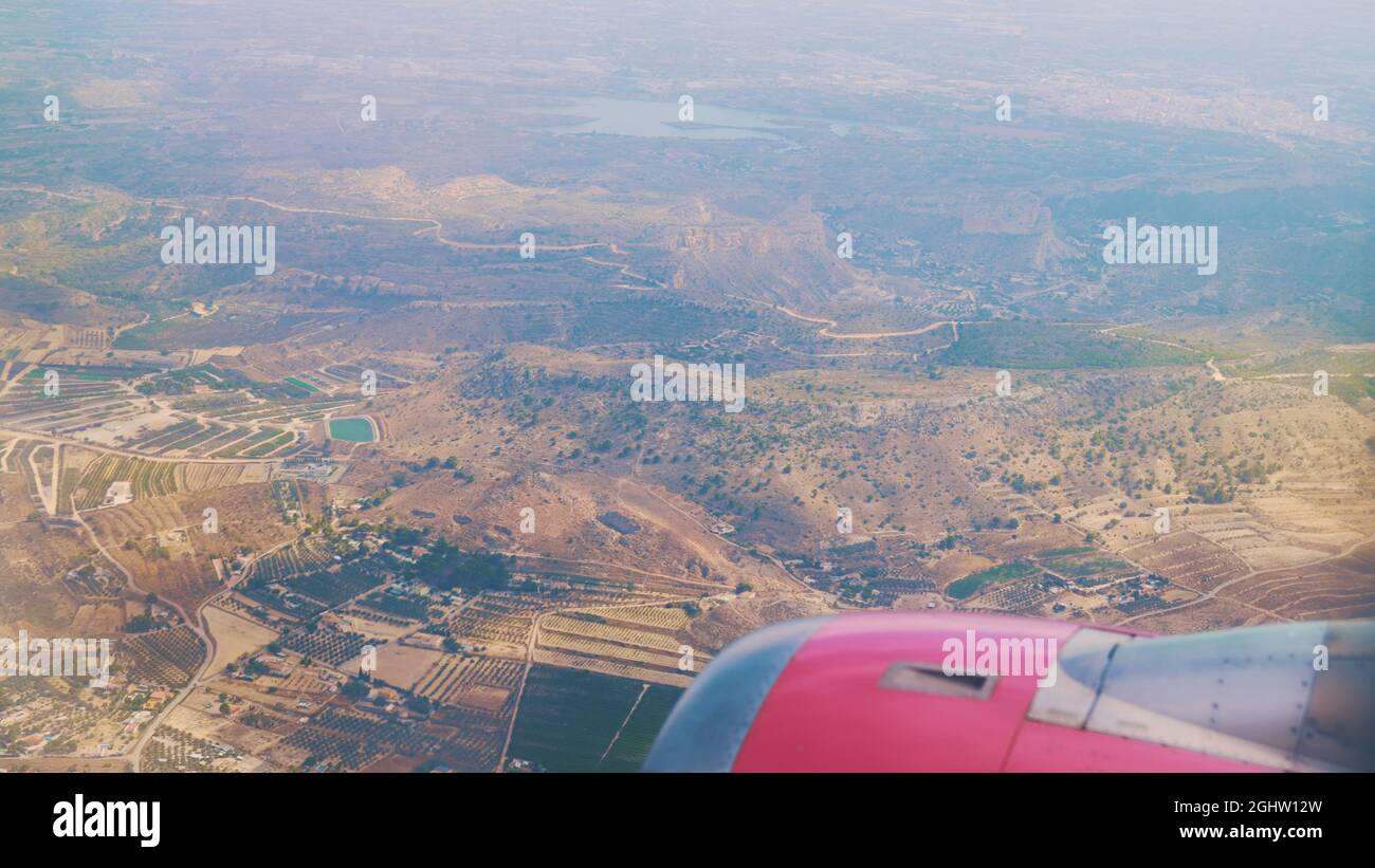 Vista aerea di Benidorm, Spagna. Le piccole case residenziali della città sono circondate da alberi. Volo aereo girato dall'aereo durante il giorno. Skyline della città. Visione offuscata a causa dell'altezza. Foto Stock