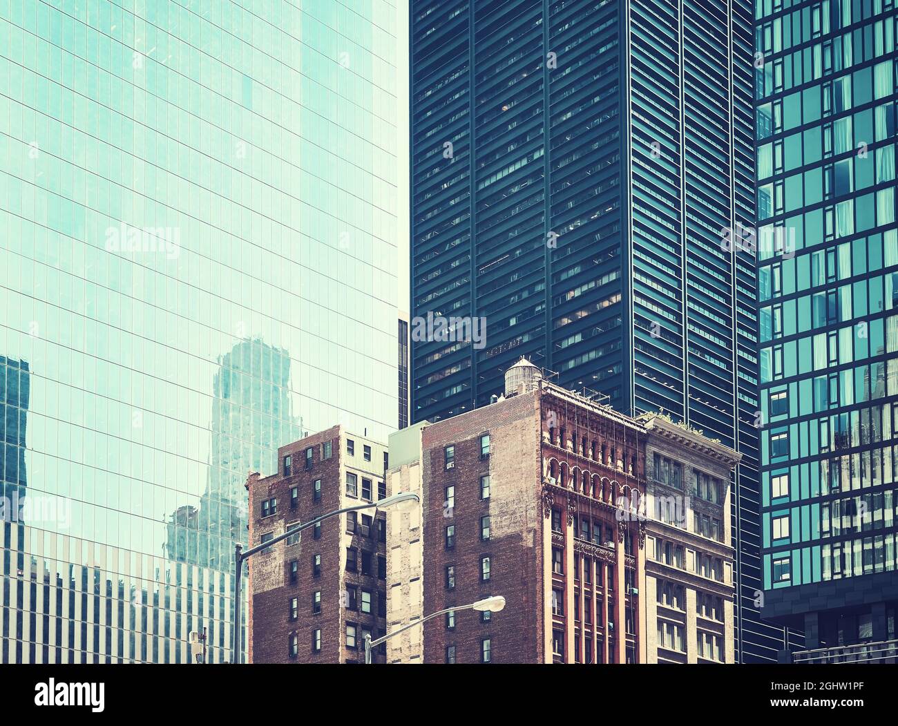 Vecchi palazzi tra grattacieli moderni a New York, foto retrò dai colori, USA. Foto Stock