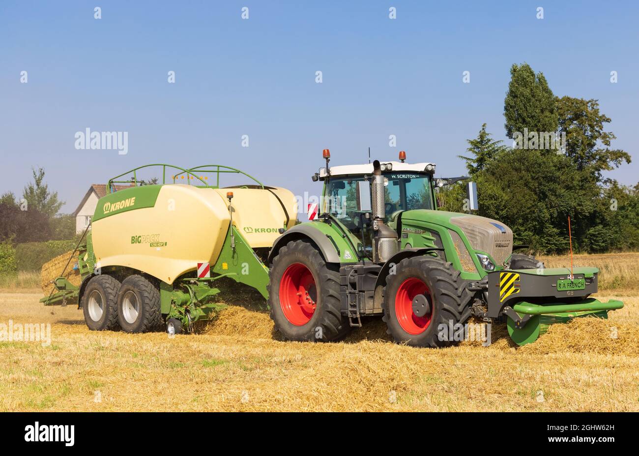 Trattore e macchina per imballaggio e imballaggio della paglia in un campo. Foto Stock