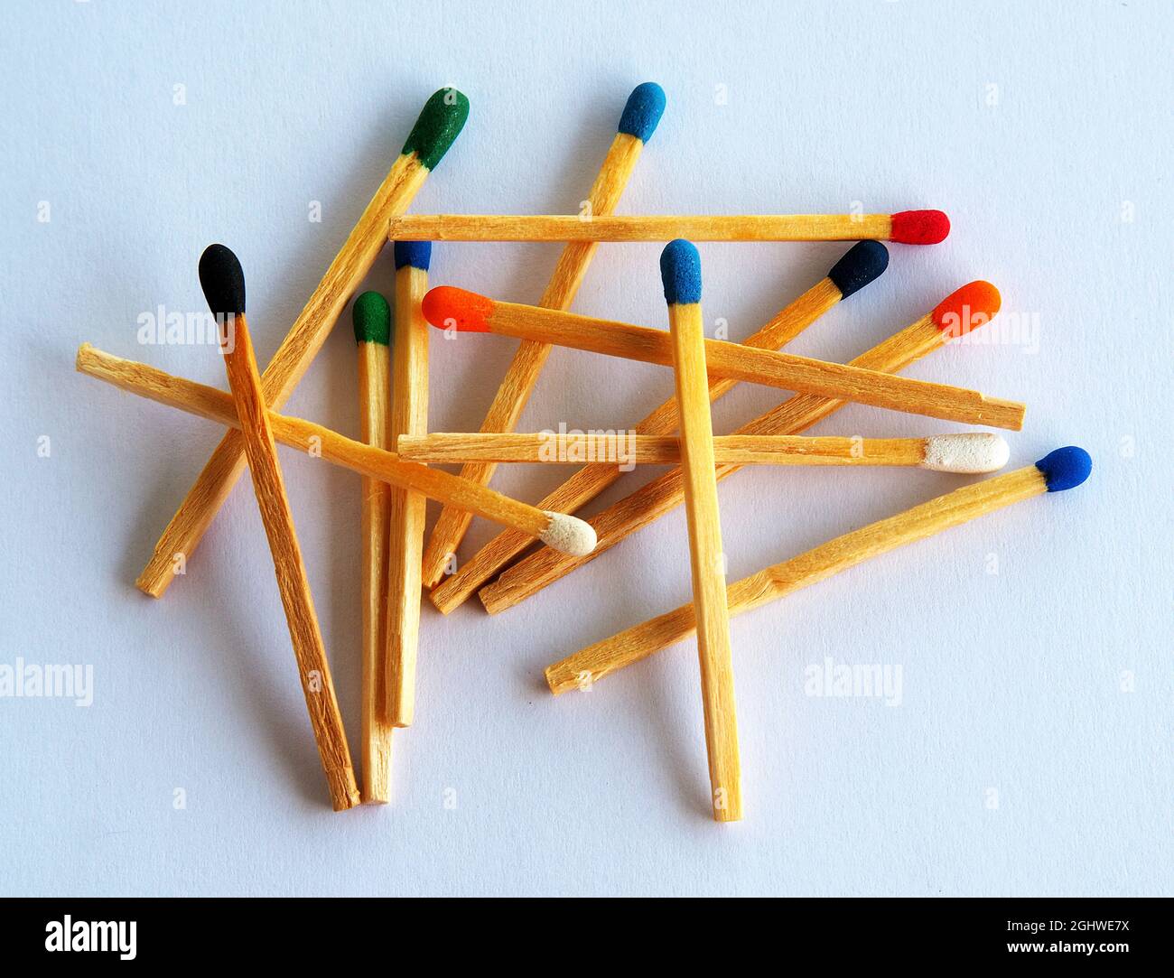 Primo piano di fiammiferi con teste di colori diversi su sfondo bianco. Foto Stock