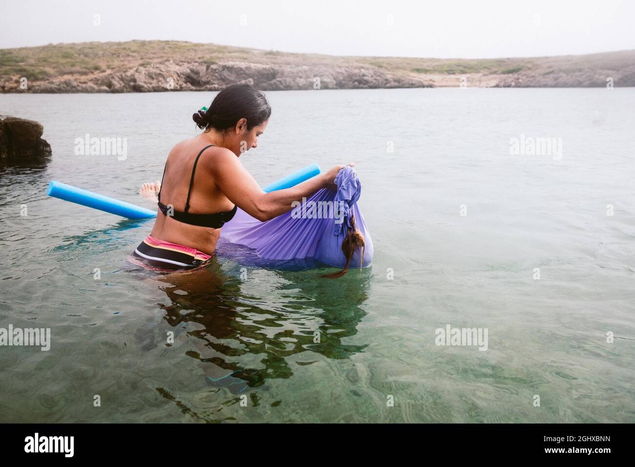 le donne galleggiano un rilassante scialle d'acqua nel mare calmo al tramonto con biliardo e scialle, una nuova tecnica curativa e rilassante Foto Stock