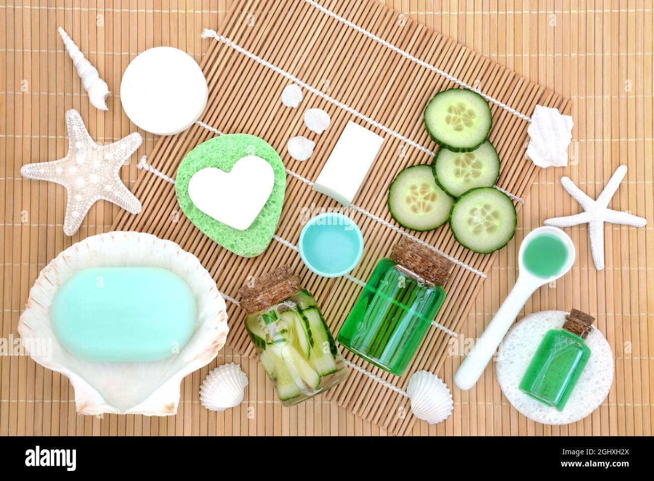 Anti invecchiamento anti rughe cetriolo trattamento estetico concetto con fette fresche, sapone, gel e spugne. Su sfondo di bambù. Foto Stock