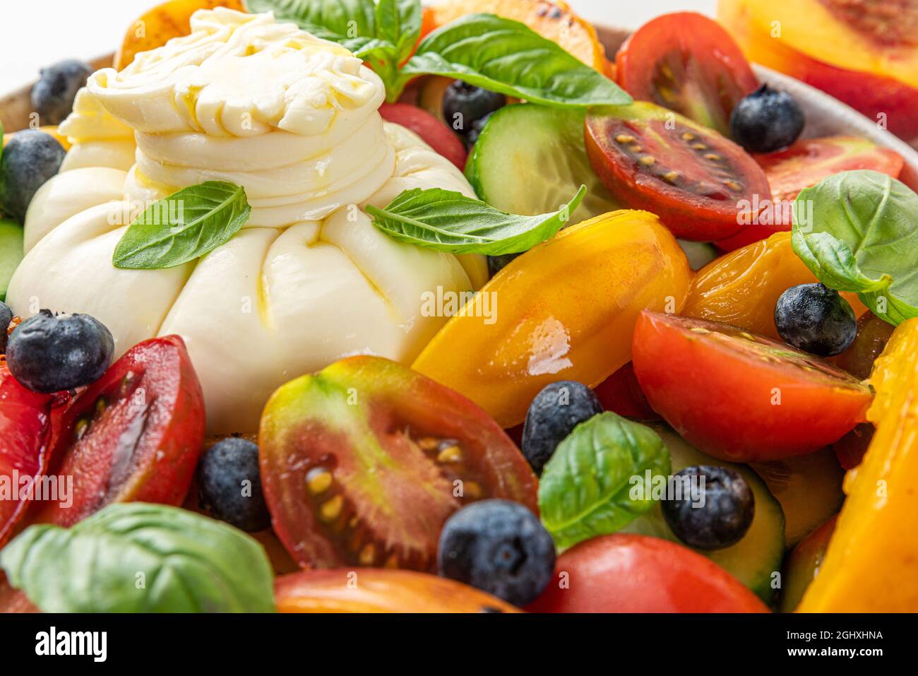 Insalata di burrata con pesche alla griglia, pomodori, mirtilli, cetrioli e basilico. Primo piano. Dieta sana concetto di cibo Foto Stock