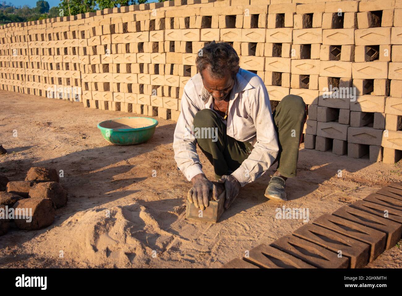 TIKAMGARH, MADHYA PRADESH, INDIA - 11 AGOSTO 2021: Uomo indiano che fa i mattoni della casa a mano usando una muffa e argilla bagnata. Foto Stock