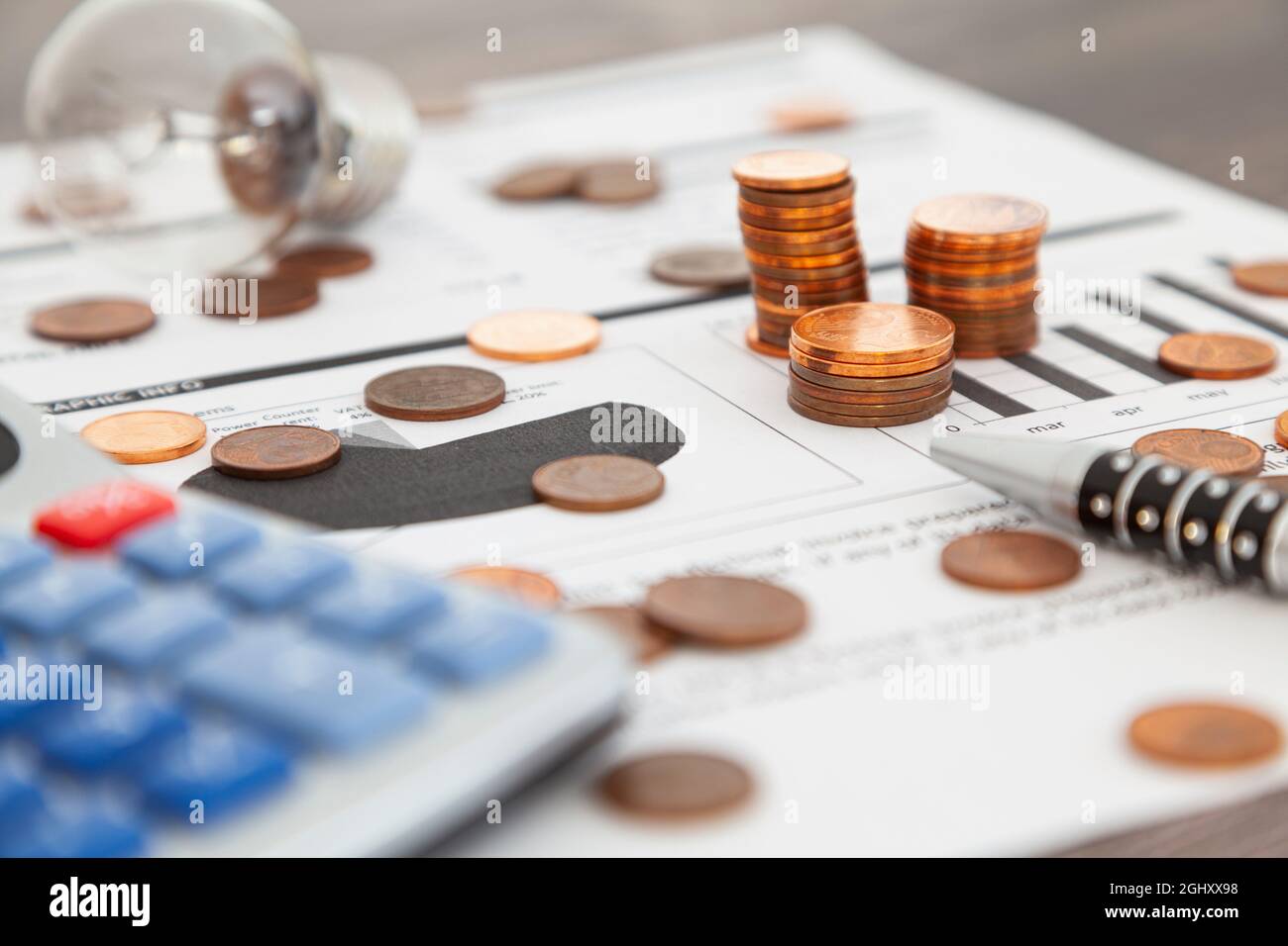 Su un conto di fornitura di energia elettrica ci sono tre pile di monete da uno, due e cinque cent e altre monete che sono sparse intorno. Parte di una penna, un Calc Foto Stock