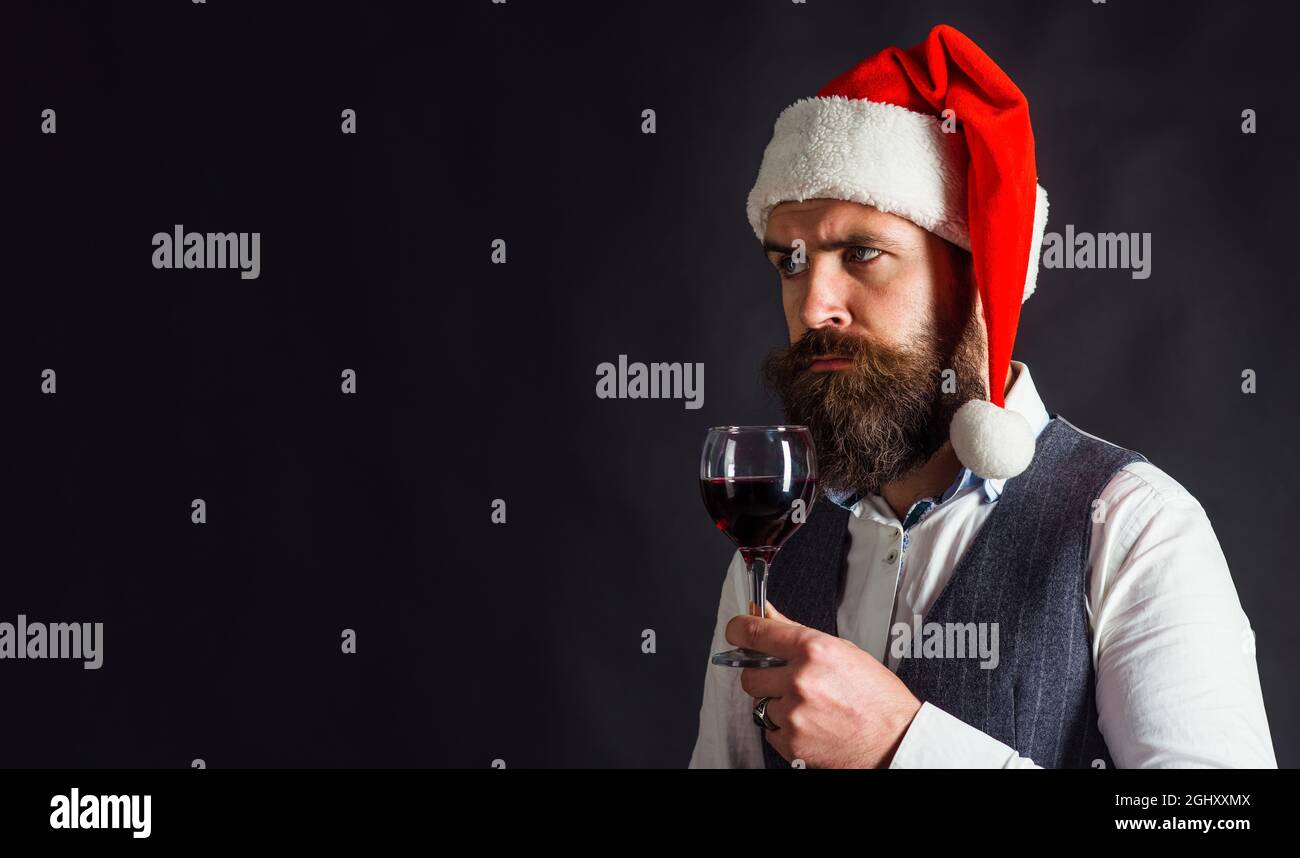 Festa di nuovo anno. Santa con bicchiere di vino rosso. Degustazione di alcol. Beded Man in Babbo Natale bevande vino. Spazio di copia. Foto Stock