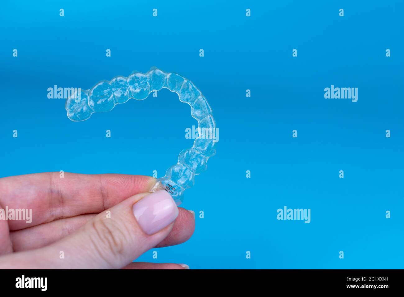 Regge a mano allineatori trasparenti invisibili rimovibili invisalign o plastici reggiseni ortodontici su sfondo blu Foto Stock