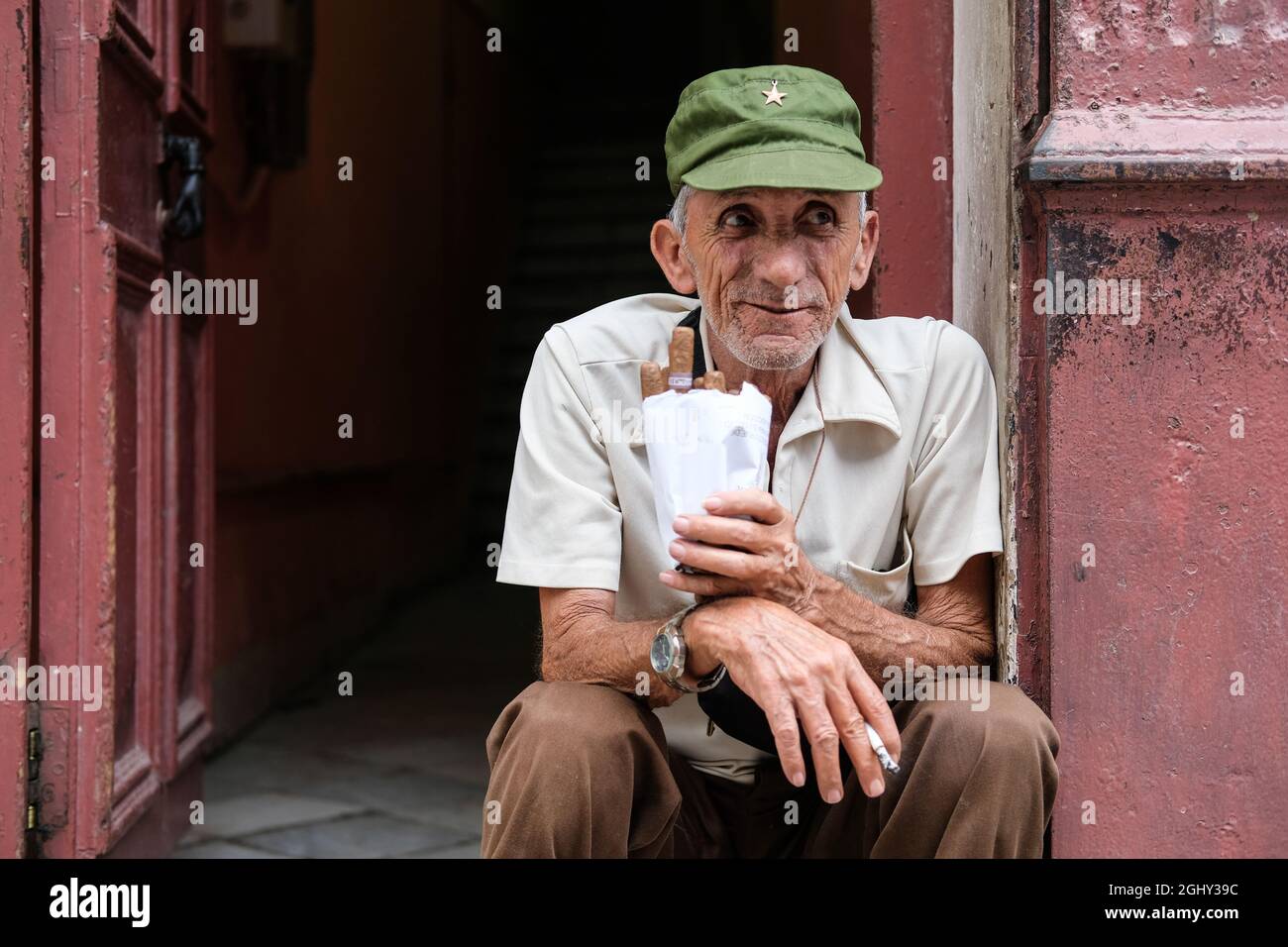 Un uomo che tiene sigari siede sulla strada a l'Avana, Cuba. Foto Stock