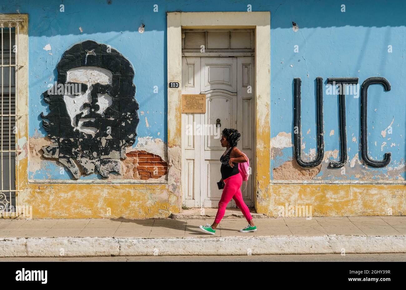Una donna cammina davanti a un'immagine di che Guevara a Trinidad, Cuba. Foto Stock