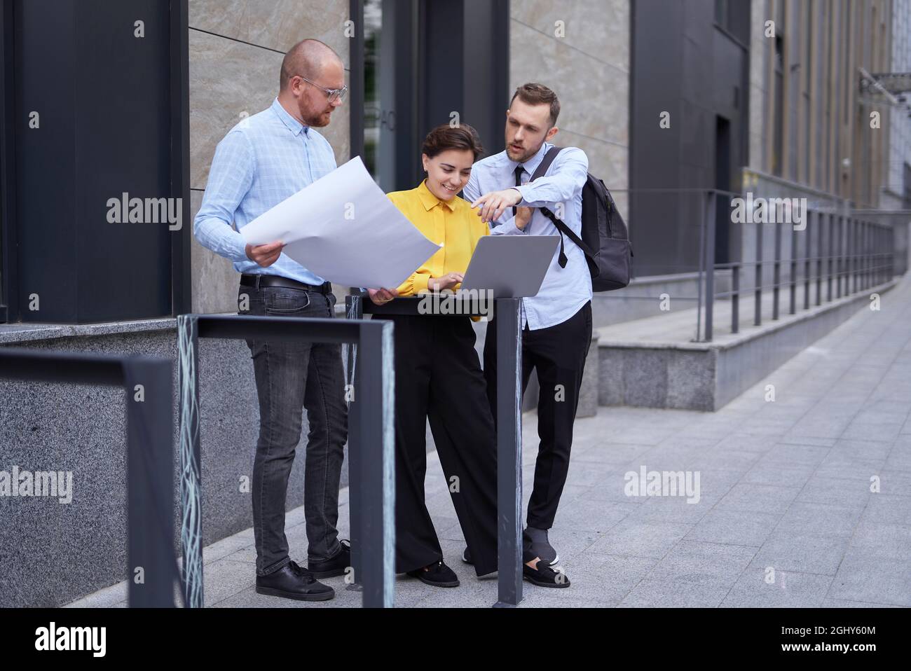 Uomini d'affari, uomini e donne in abiti casual in piedi fuori ufficio, brainstorming. Gli architetti o i progettisti si occupano di progettare il progetto e il notebook come presentazione. Foto di alta qualità Foto Stock
