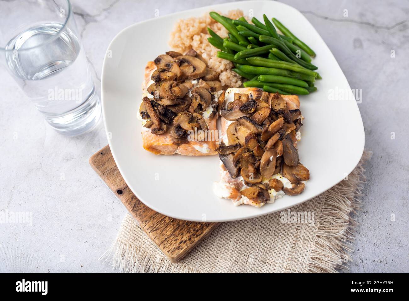 Cena al salmone con riso marrone e fagioli verdi, condita con yogurt greco e funghi. Foto Stock