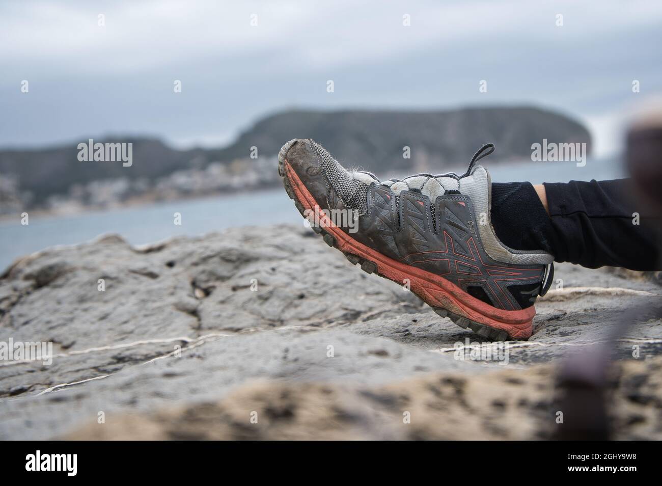 piede in scarpa da trekking sulle rocce con sfondo sfocato. ritratto Foto Stock