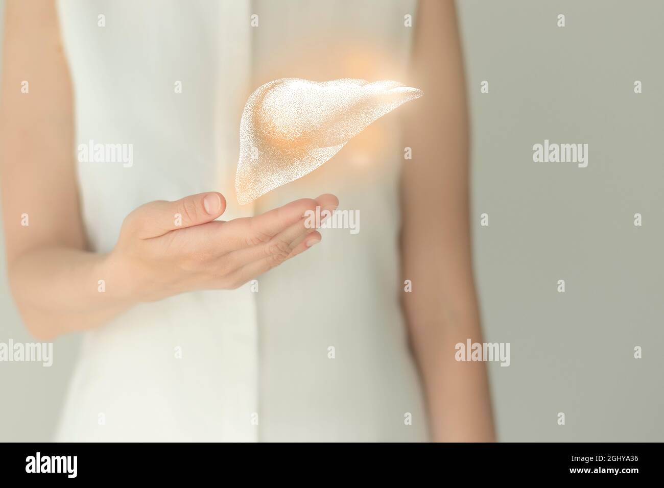 Paziente femminile irriconoscibile in abiti bianchi, evidenziato fegato di mano nelle mani. Concetto di problemi del sistema digestivo umano. Foto Stock