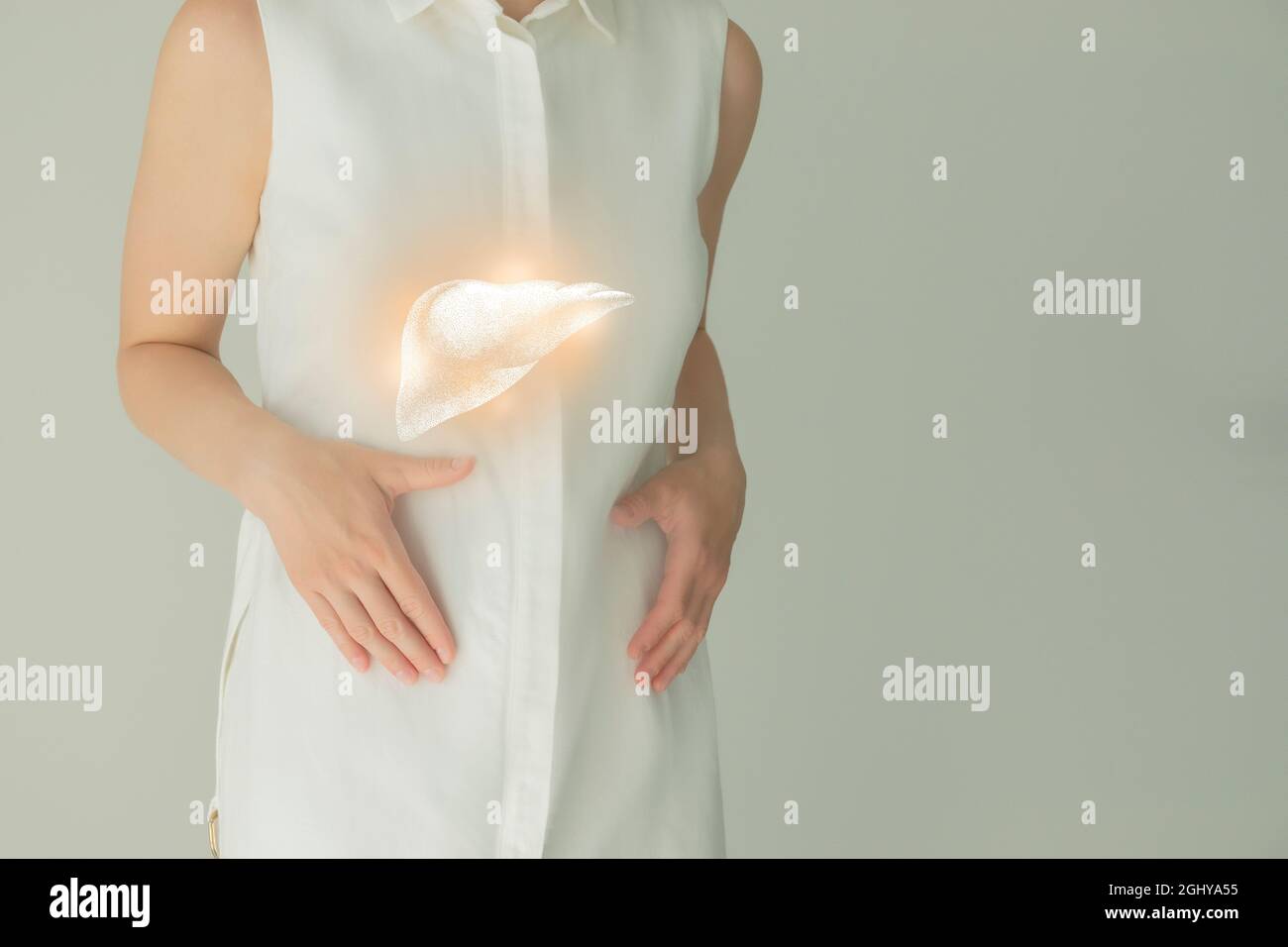Paziente femminile irriconoscibile in abiti bianchi, evidenziato fegato di mano nelle mani. Concetto di problemi del sistema digestivo umano. Foto Stock