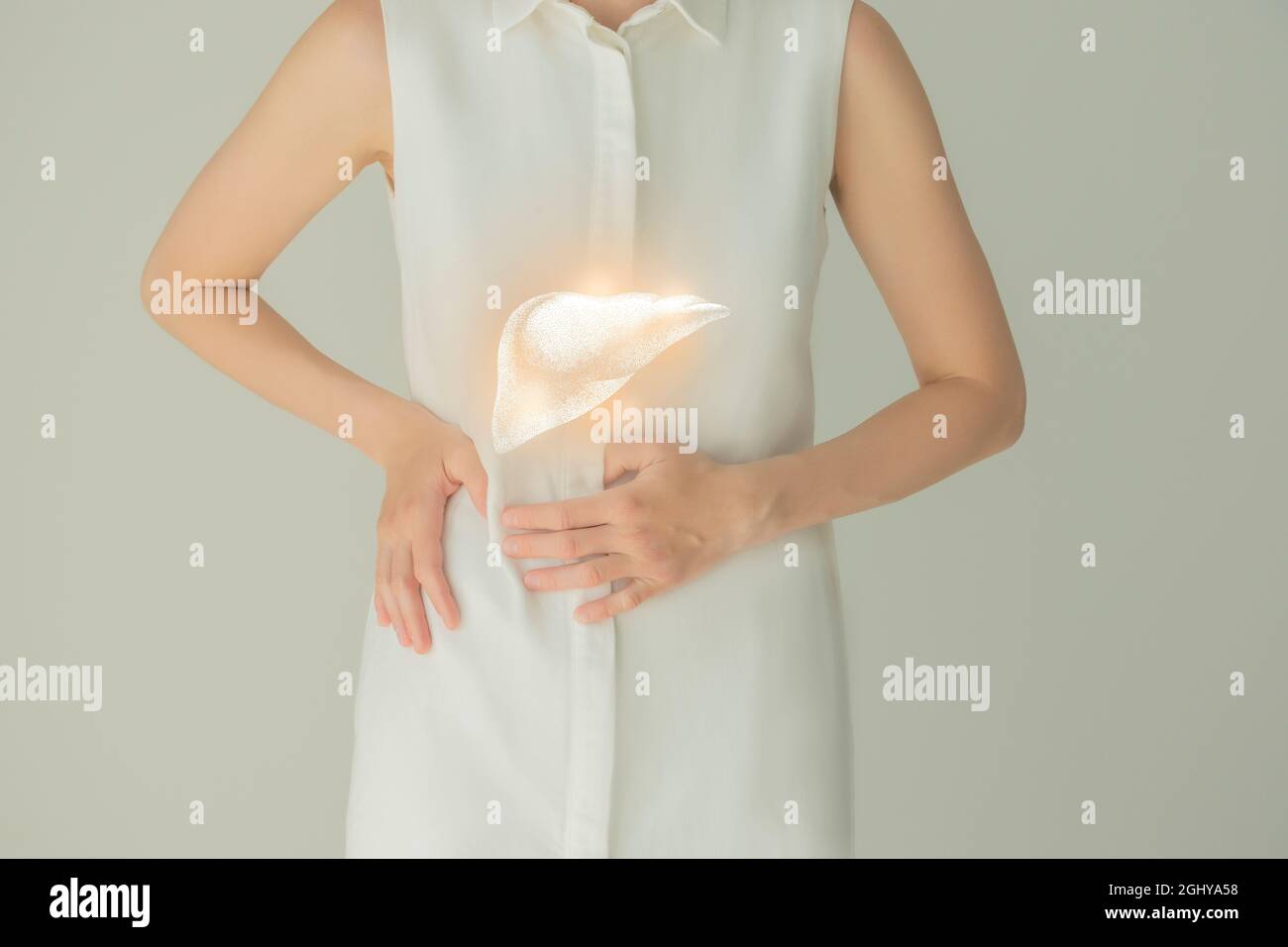 Paziente femminile irriconoscibile in abiti bianchi, evidenziato fegato di mano nelle mani. Concetto di problemi del sistema digestivo umano. Foto Stock