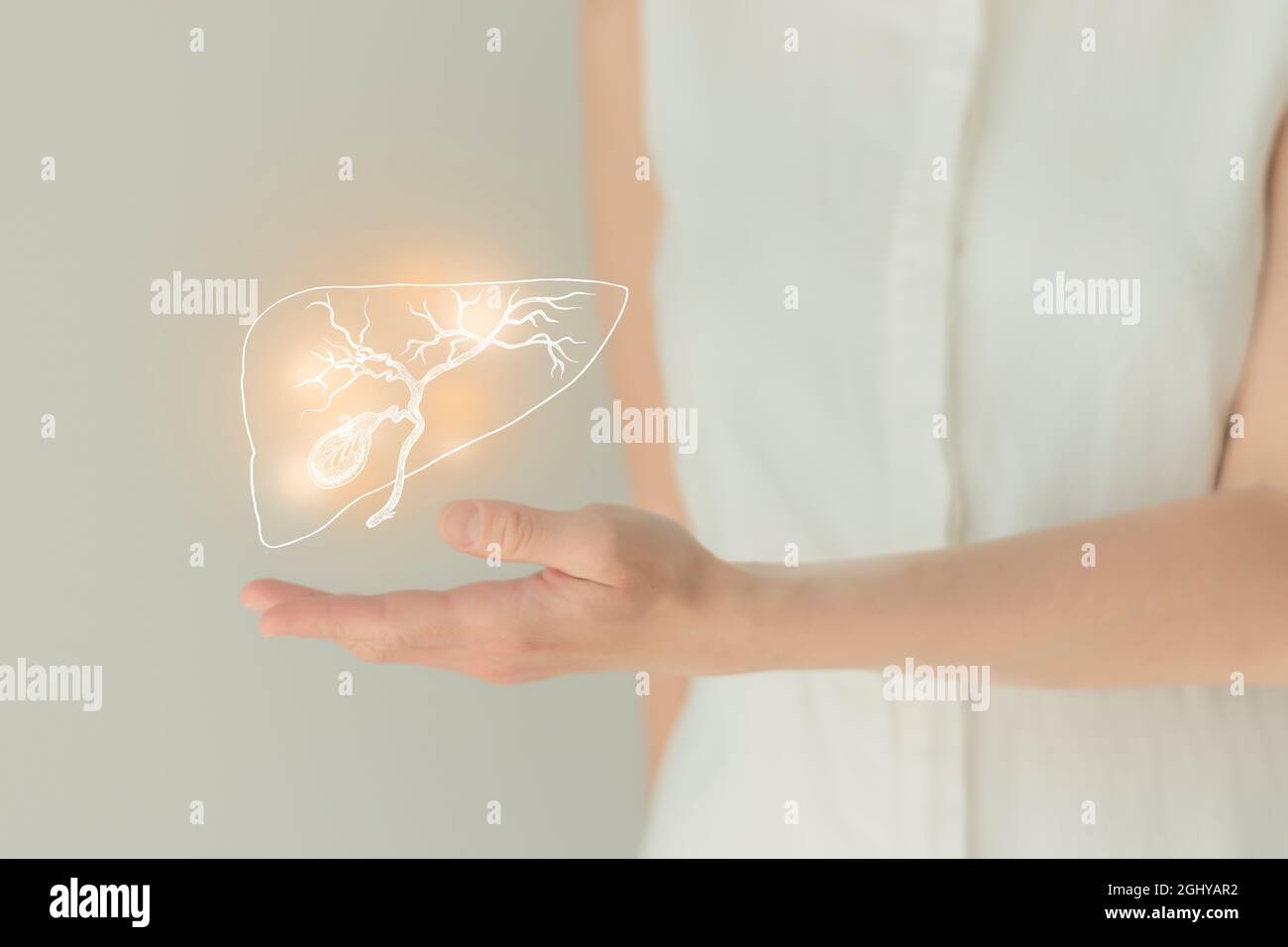 Paziente femminile irriconoscibile in abiti bianchi, evidenziata la cistifellea di corbone nelle mani. Concetto di problemi del sistema digestivo umano. Foto Stock