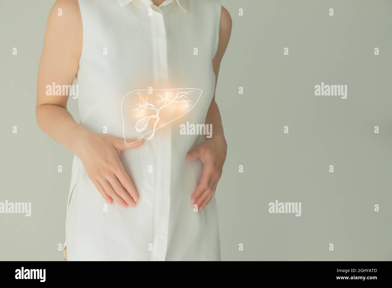 Paziente femminile irriconoscibile in abiti bianchi, evidenziata la cistifellea di corbone nelle mani. Concetto di problemi del sistema digestivo umano. Foto Stock