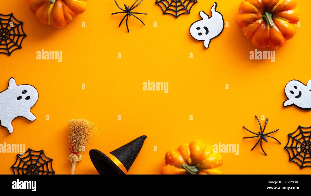 Buon Halloween carta disegno mockup. Piatto Lay, vista dall'alto fantasmi, ragnatela, zucche, cappello da strega e scopa su sfondo arancione. Foto Stock