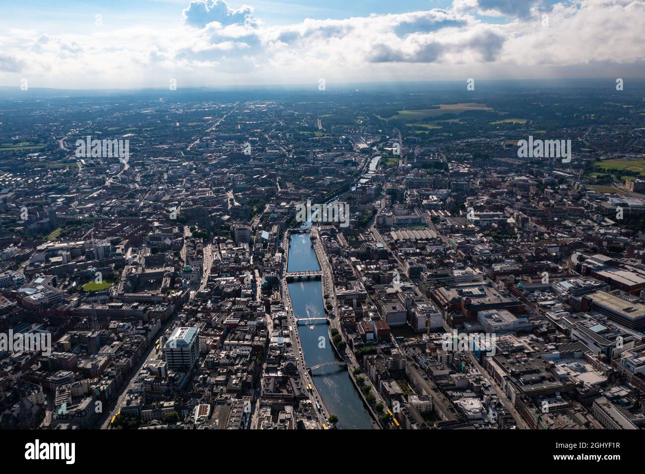 Vista aerea dello skyline di Dublino con fiume che scorre con ponte che collega due lati della strada circondato da edifici durante una giornata nuvolosa Foto Stock