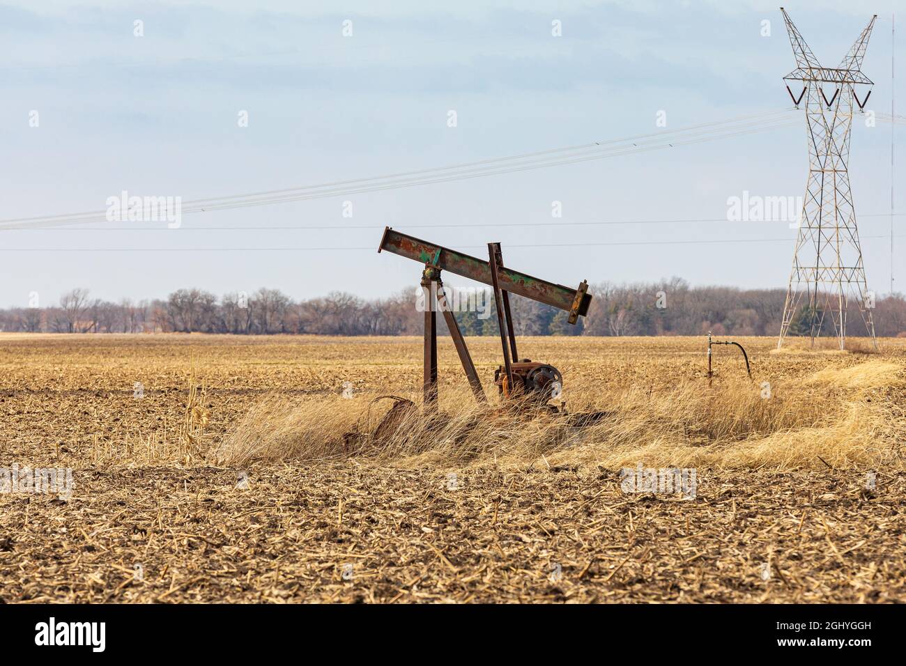 Vecchio, petrolio orfano bene pompa in campo di fattoria. Petrolio bene abbandono, smantellamento, e petrolio produzione concetto. Foto Stock