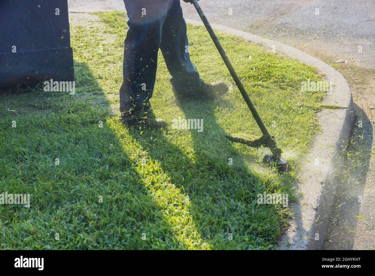 L'uomo da giardinaggio taglia l'erba con un rasaerba manuale. Foto Stock