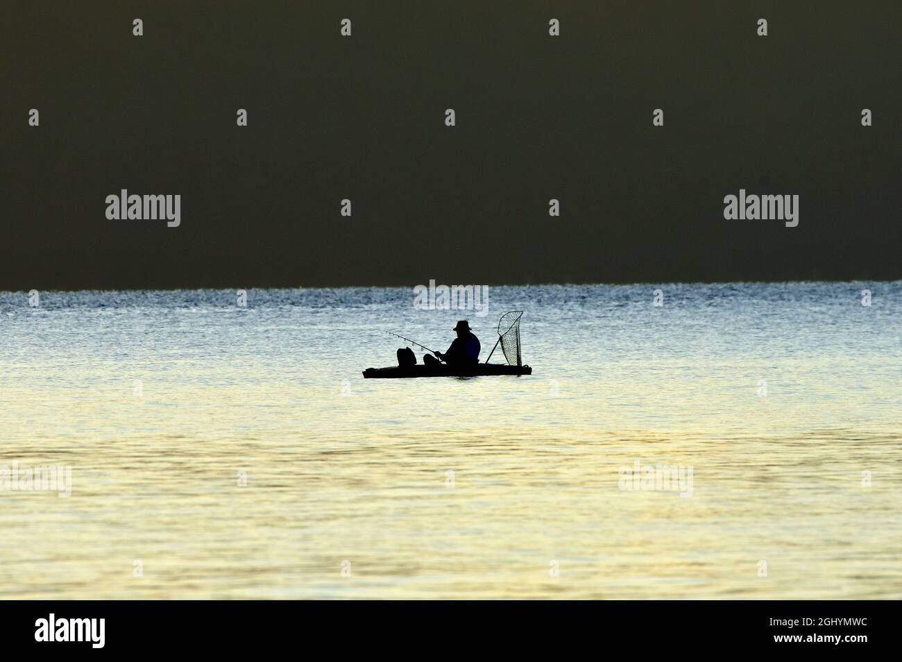 Una silhouette di un uomo che pesca da una barca di gomma nel canale Stewart sulla costa dell'isola di Vancouver British Columbia Canada. Foto Stock