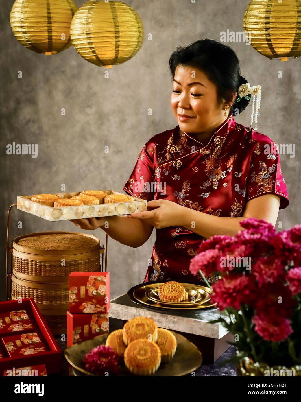 Una signora Peranakan cinese che tiene un piatto di torte di mooncake per il Mid-Autumn Festival Foto Stock