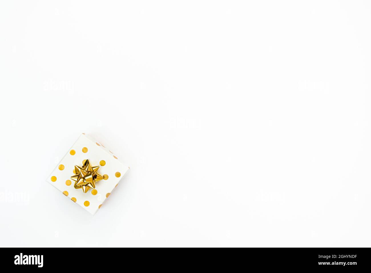 Vista dall'alto di una confezione regalo punteggiata d'oro su sfondo bianco. Spazio di copia. Foto Stock