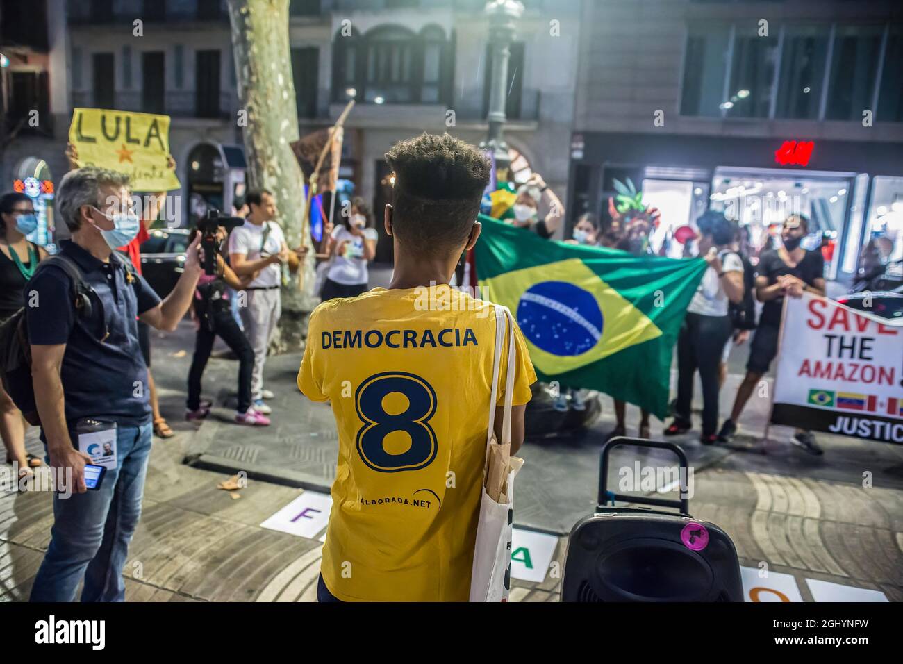 Un manifestante si trova di fronte alla bandiera brasiliana con una camicia scritta, democrazia durante la dimostrazione. Il giorno dell'indipendenza del Brasile, il 7 settembre, il presidente del Brasile, Jair Bolsonaro, ha convocato i suoi sostenitori in manifestazioni in tutto il paese e incita minacce alla democrazia e un possibile colpo di Stato. Diversi gruppi e partiti politici del paese hanno reagito contro e invocato manifestazioni contro il presidente, a Barcellona un gruppo di brasiliani ha compiuto un atto contro il presidente delle Ramblas. (Foto di Thiago Prudencio/SOPA Images/si Foto Stock