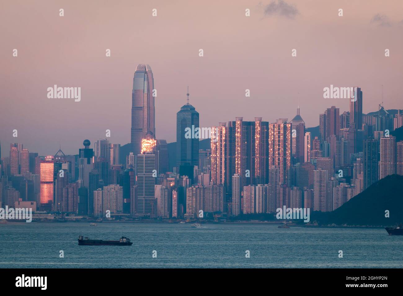 Il sole tramontato si riflette in alti edifici sull'Isola di Hong Kong, con un cielo rosa in Oriente a causa del fenomeno della 'cintura di Venere' Foto Stock