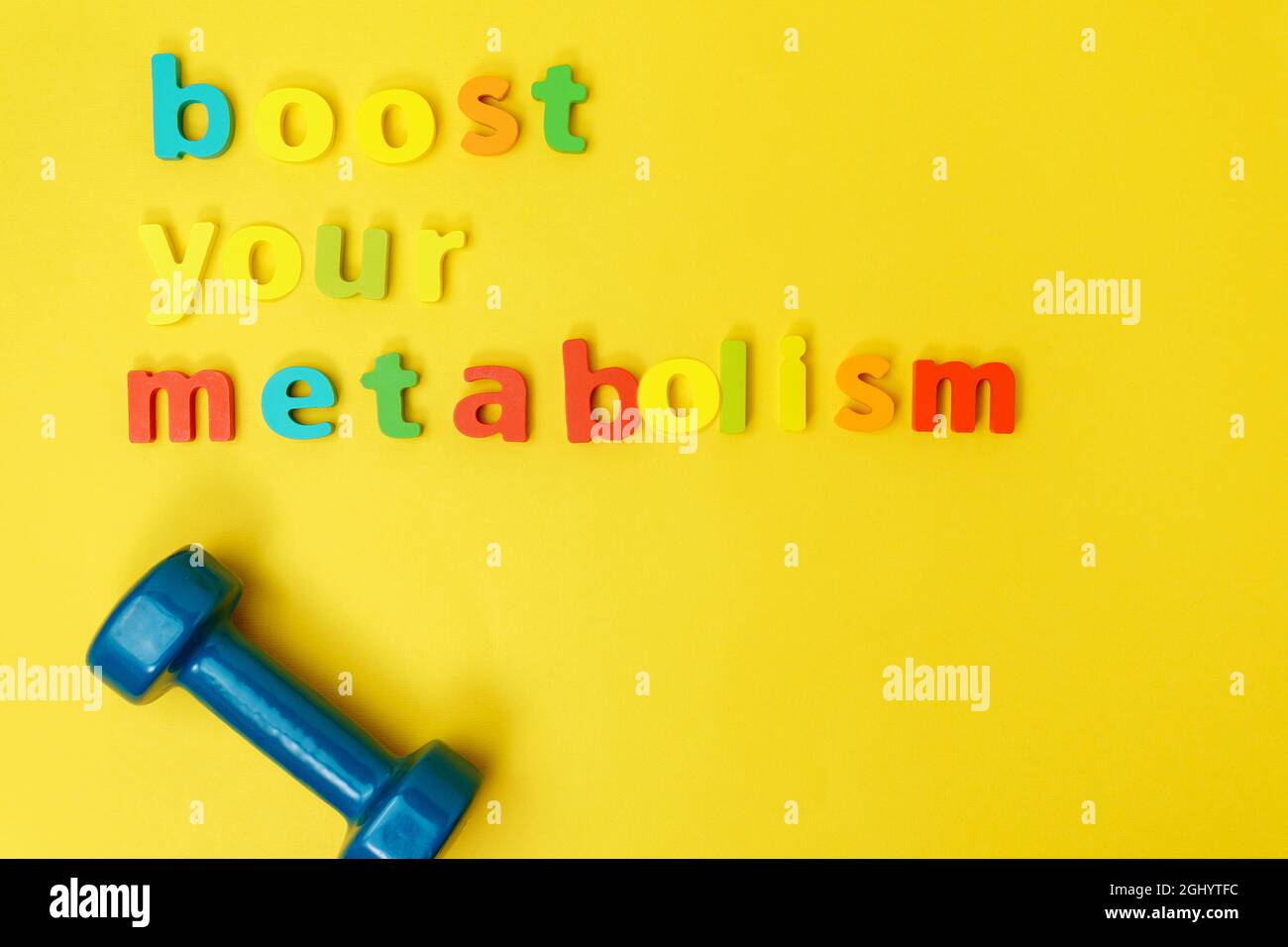 Aumenta il metabolismo, lo sport e il dumbbell. Vista dall'alto. Sfondo giallo. Spazio copia Foto Stock