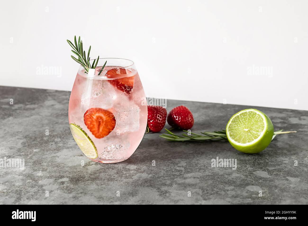 Cocktail in gin rosa con fragole e rosmarino, drink rinfrescante con alcol,  ghiaccio e lime. Spazio per fotocopie Foto stock - Alamy