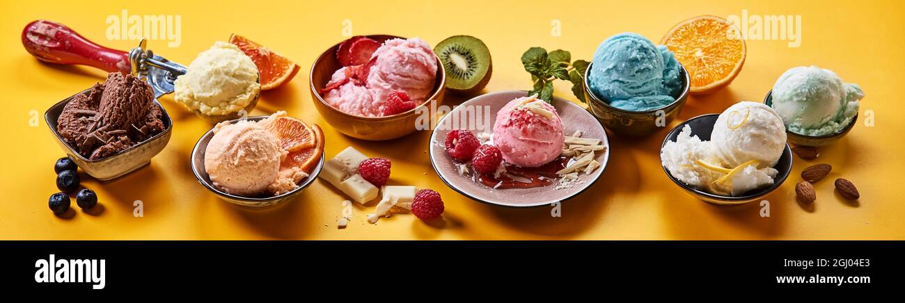 Una selezione gourmet di cremosi gelati italiani con sapori di frutta e cioccolato assortiti serviti in piatti individuali con ingredienti freschi su un colorfu Foto Stock
