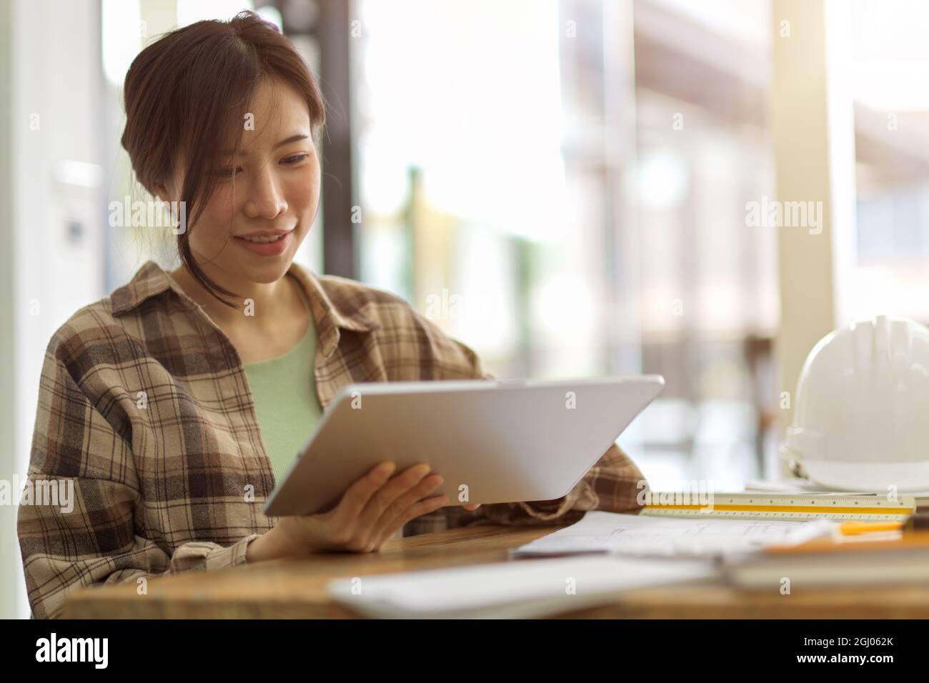 Ingegnere professionale femminile che lavora su tablet digitali in ufficio, attrezzature ingegneristiche, cantiere sfocato in background Foto Stock