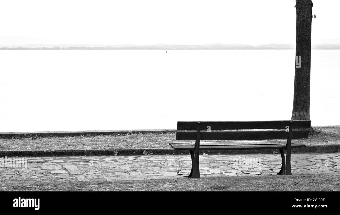 Una panca in legno vuota in un parco affacciato sul Lago Trasimeno (Umbria, Italia, Europa) Foto Stock
