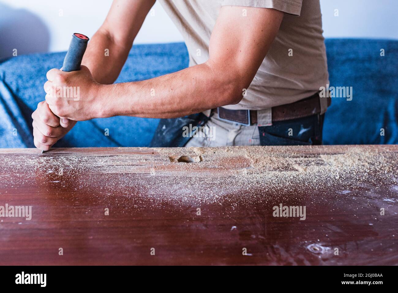 Uomo che esegue una sguainatura della vernice di una porta di legno. Levigatura smalto. Foto Stock