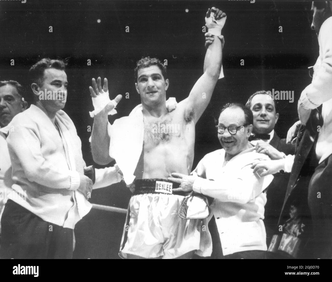 Rocky Marciano di Chicago è ancora campione di pesi massimi dopo un breve scuffo con il contendente Jersey Joe Walcott, ha la mano sollevata in vittoria. L'addestratore Charley Goldman (occhiali) è al suo fianco. Walcott è stato contato a 2 minuti e 25 secondi del primo turno. 17 maggio 1953 Foto Stock