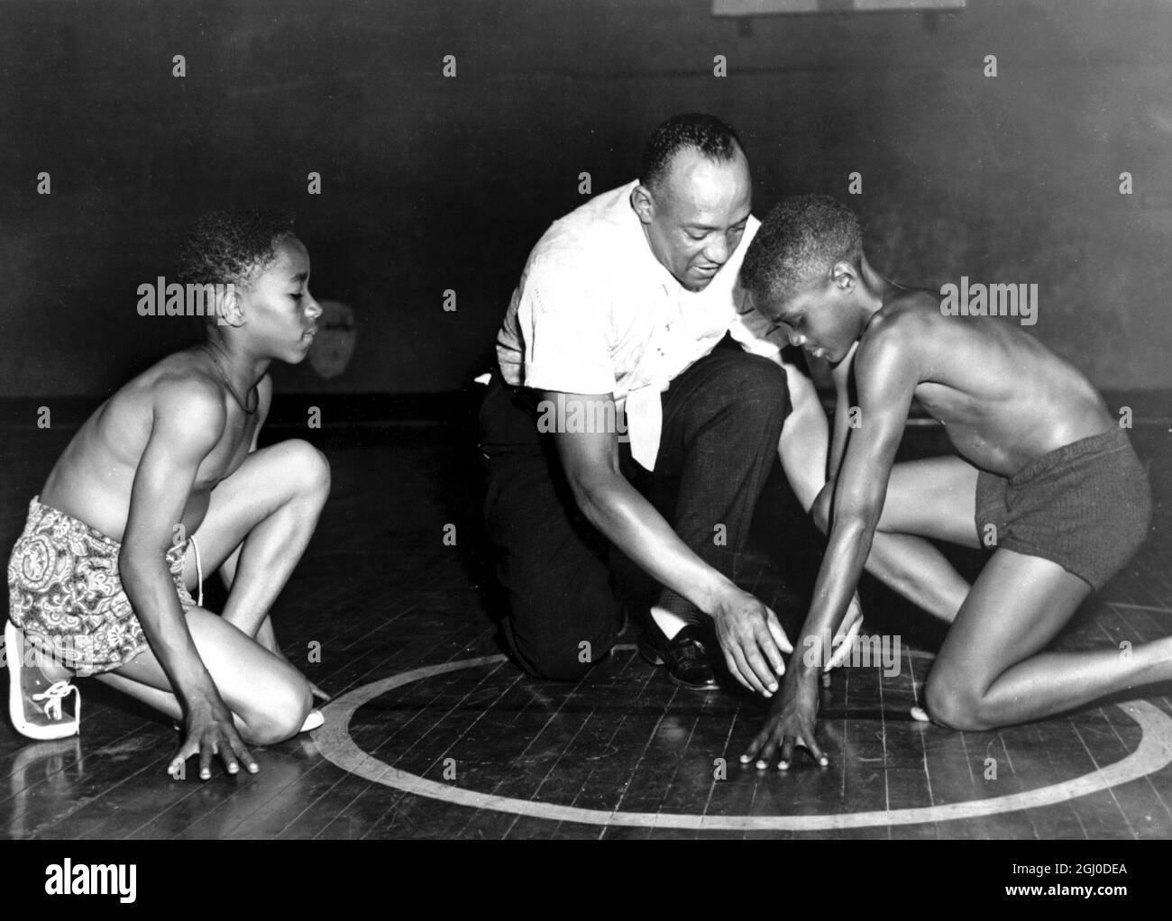 Jesse Owens, la grande star del circuito olimpico americano, mostra a due ragazzi del South Side Boys Club la posizione di partenza che gli ha portato fama. Rajah Latimore (a sinistra) Sherman Davis 1 luglio 1954 Foto Stock