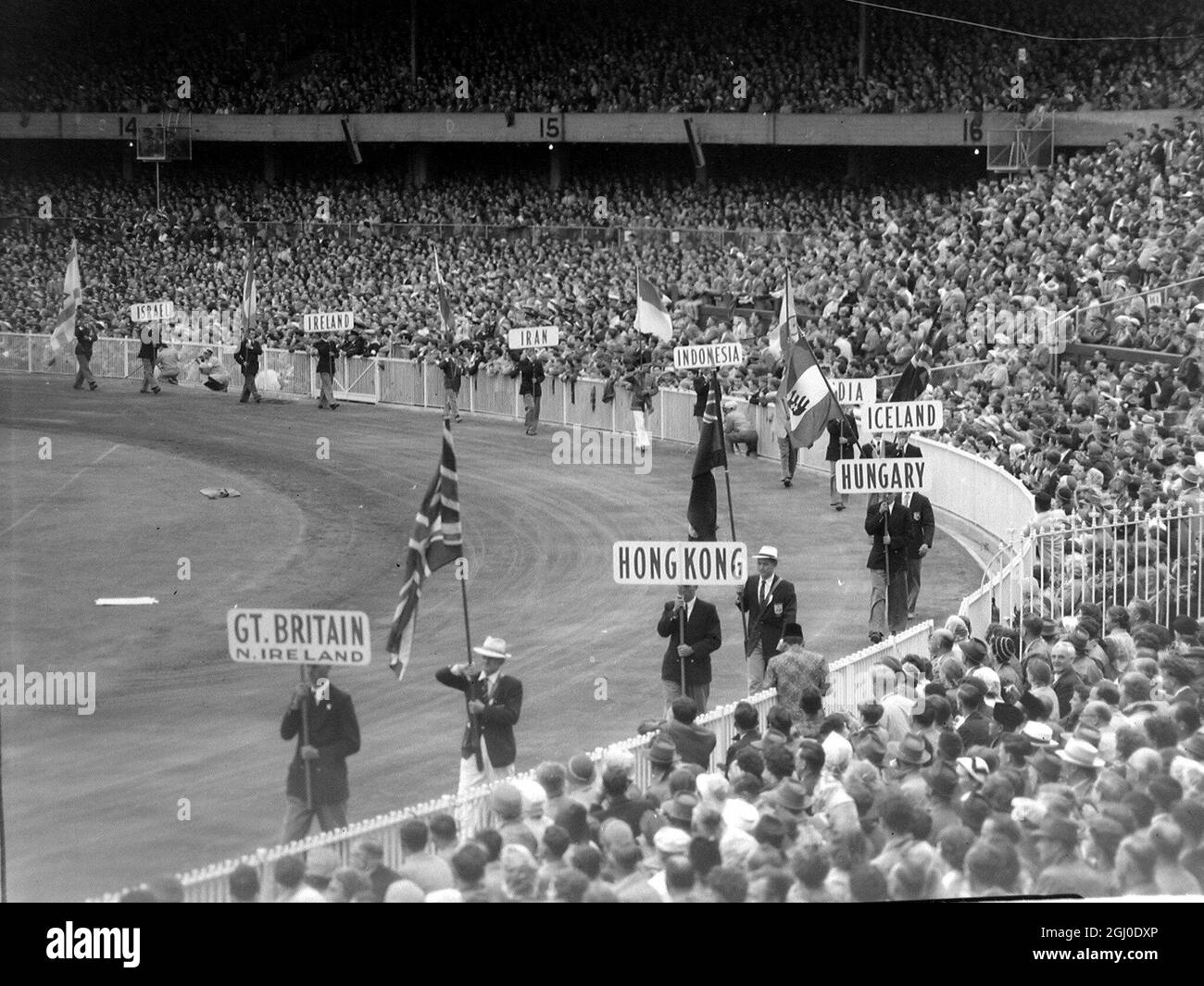 Melbourne Olympic Games 1956 gli standard e le bandiere delle nazioni in competizione sono trasportati intorno al campo di Cricket di Melbourne durante la cerimonia di chiusura. 13 dicembre 1956 Foto Stock
