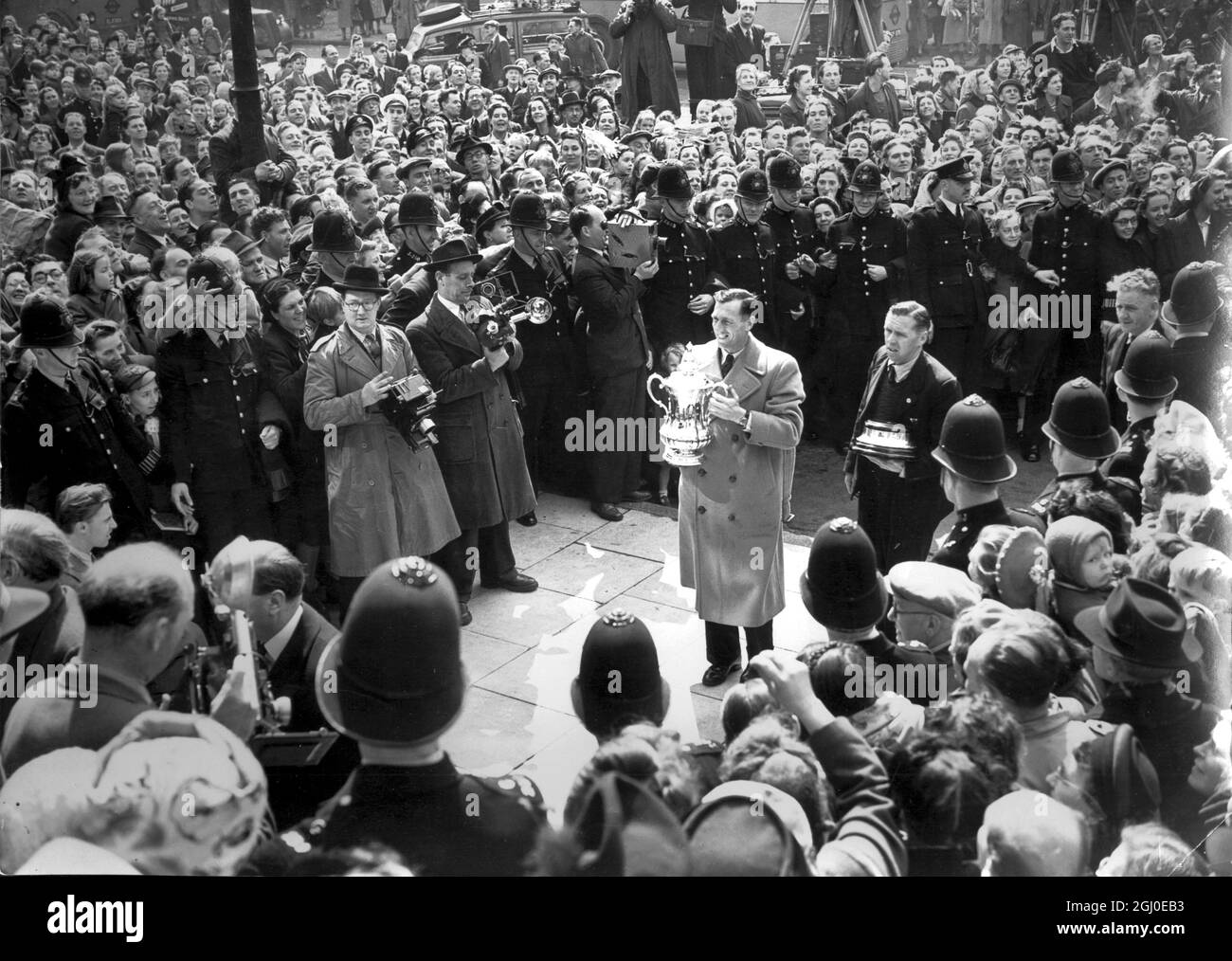 I vincitori dell'Arsenal Football Club nella finale della Coppa del Sabato a Wembley, hanno ricevuto un ricevimento civico dal Sindaco e dalla Coporazione di Islington al Municipio. Joe Mercer, il capitano dell'Arsenale, porta la coppa nel municipio tra le folle allegre e i poliziotti. 2 maggio 1950. Foto Stock