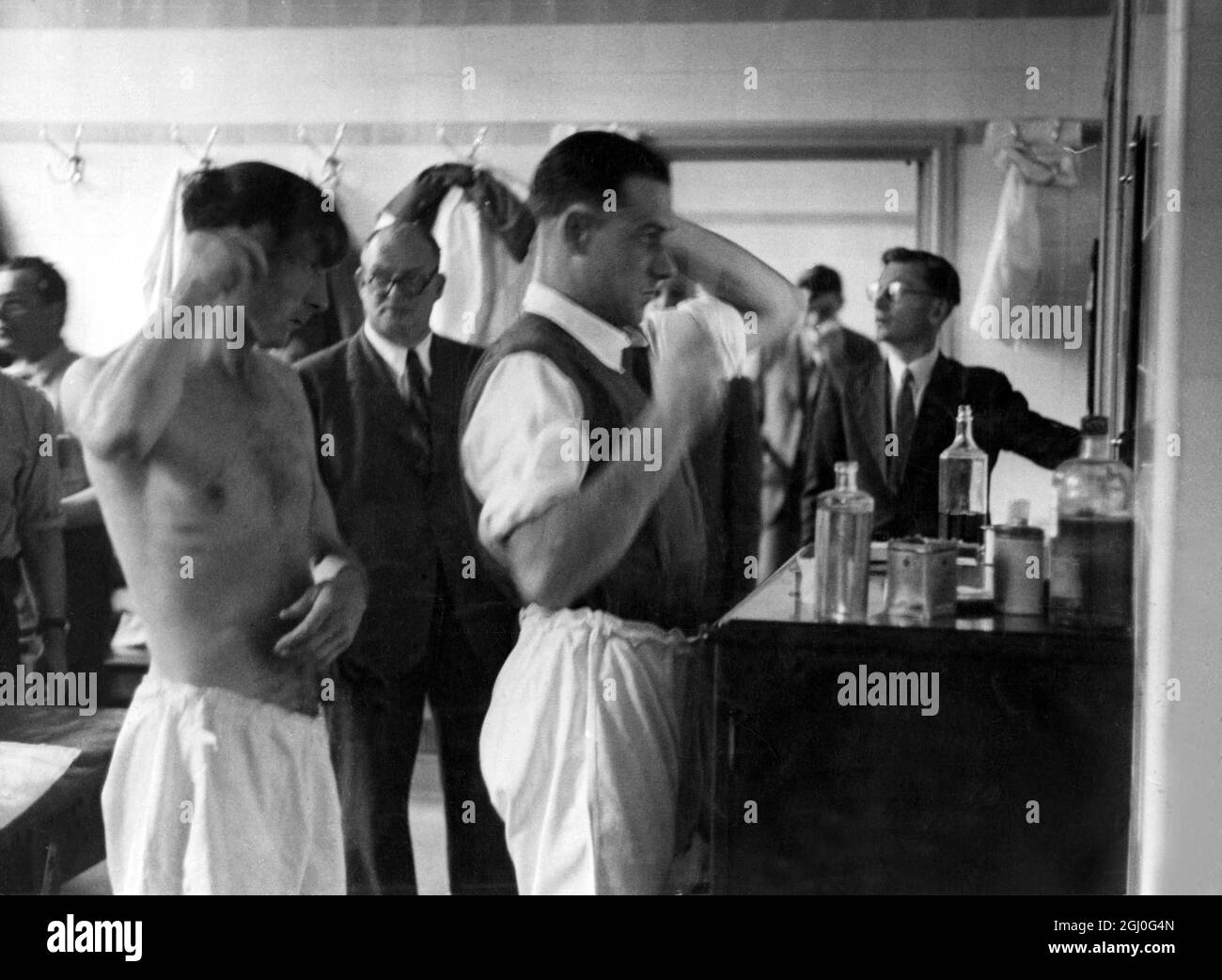 I giocatori di Arsenal nel loro spogliatoio - Tom Whittaker, il manager dà istruzioni last minute come Joe Mercer e McPherson condividono il pennello, pettine e specchio! 1947 Foto Stock