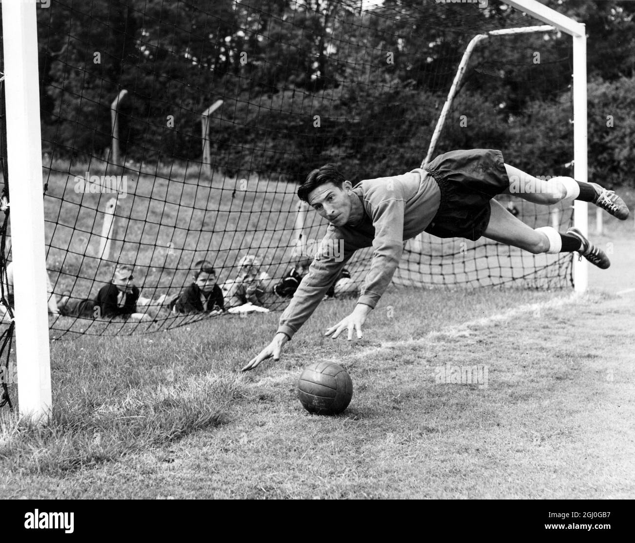 Tottenham Hotspur in allenamento per la stagione 1962-63. Una linea di giovani si allunga dietro l'obiettivo per guardare Bill Brown in azione. 3 agosto 1962 Foto Stock