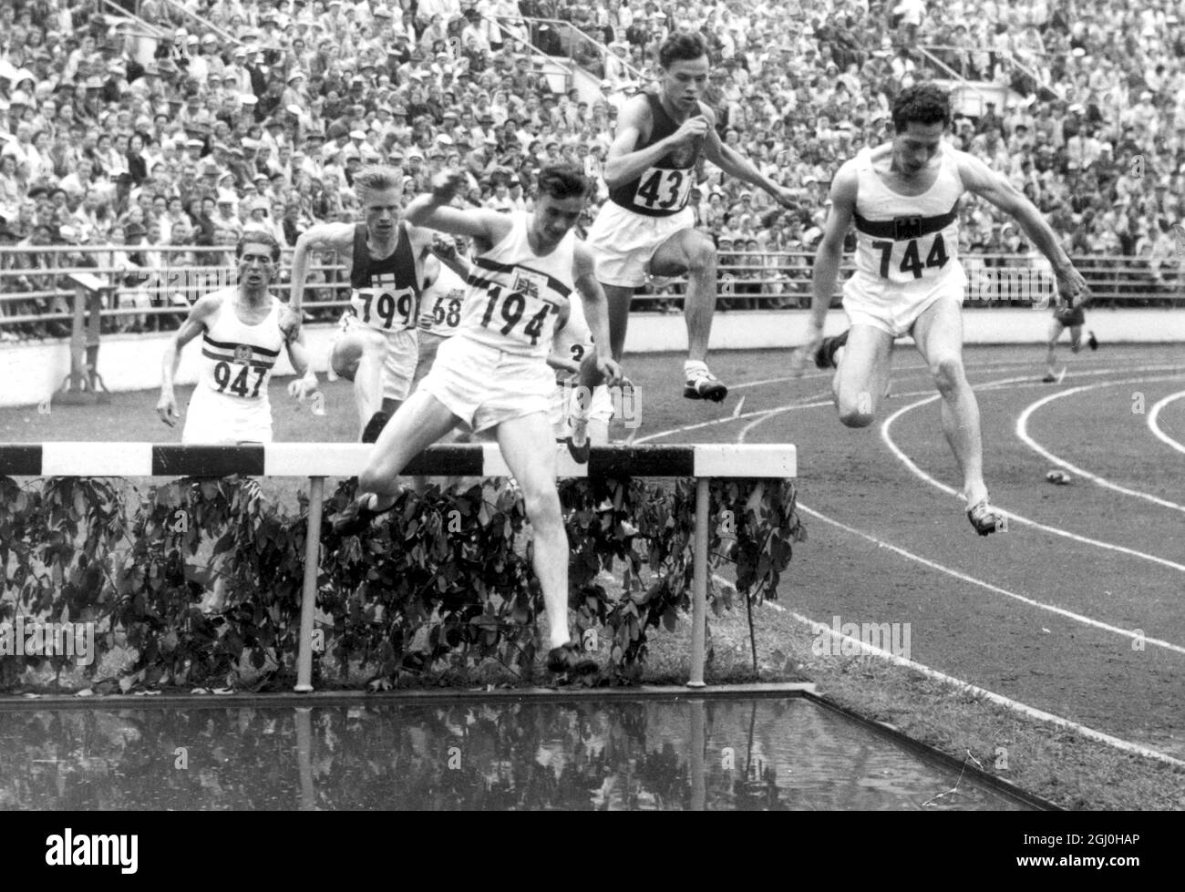 Helsinki: John Disley britannico (194) prendendo l'ultimo ostacolo nel secondo calore della steeplechase 3,000 metri. Il concorrente n. 799 è 0.0. Pinteenpaa, di Finlandia. Tempo di Disley di 8 minuti 59.4 sec. Impostare un nuovo record Olymipc per questo evento. 24 luglio 1952 Foto Stock